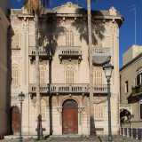 L'edificio, dai colori grigio e rosa, mescola diversi generi architettonici...